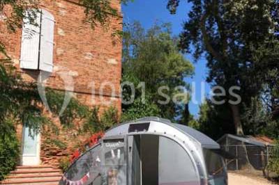 Église en briques rouges avec clocher-mur, entourée d'arbres et située dans un environnement rural.