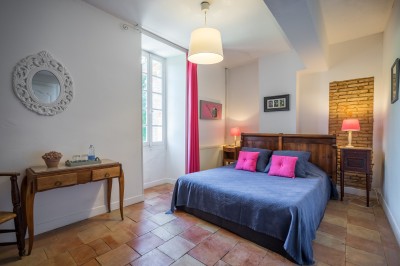 Piscine extérieure entourée de bois et de végétation, avec des transats sous une pergola en bois.
