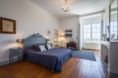 Piscine extérieure entourée de bois et de végétation, avec des transats sous une pergola en bois.