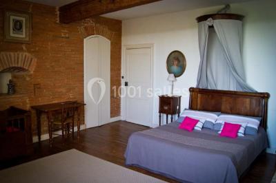 Statue en pierre près d'un escalier en briques, avec des hortensias roses en pots au premier plan.