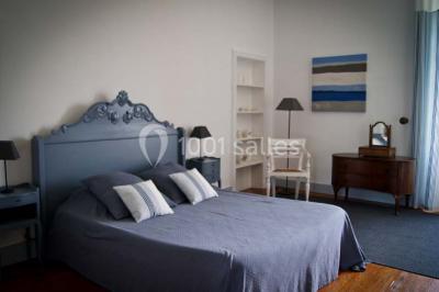 Statue en pierre près d'un escalier en briques, avec des hortensias roses en pots au premier plan.