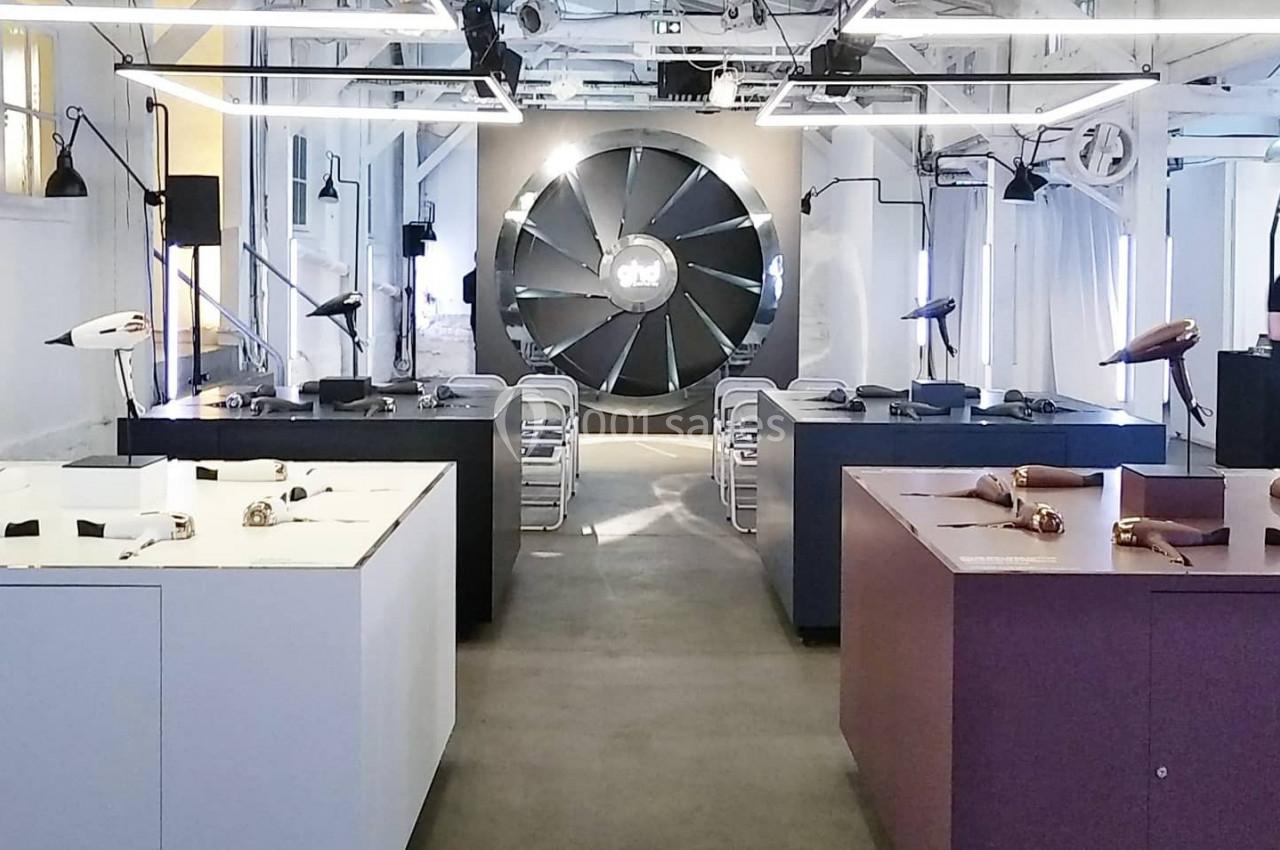 Salle d'exposition moderne avec des meubles et objets design, éclairée par une lumière naturelle et artificielle.