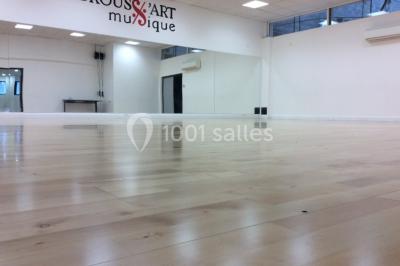 Vue d'un jardin clôturé avec pelouse, deux pots rouges contenant des plantes et un premier plan de feuilles vertes.