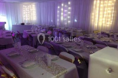 Vue d'un jardin clôturé avec pelouse, deux pots rouges contenant des plantes et un premier plan de feuilles vertes.