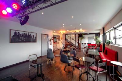 Vue d'un jardin clôturé avec pelouse, deux pots rouges contenant des plantes et un premier plan de feuilles vertes.