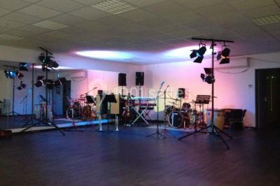 Vue d'un jardin clôturé avec pelouse, deux pots rouges contenant des plantes et un premier plan de feuilles vertes.