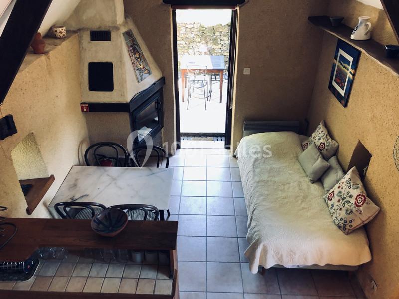 Vue d'une pièce chaleureuse avec table, cheminée, canapé et accès à une terrasse extérieure.