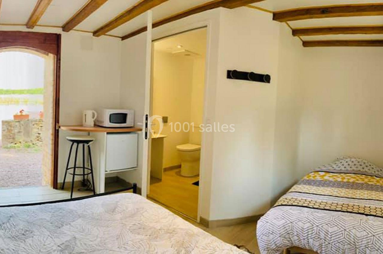 Chambre lumineuse avec deux lits, kitchenette équipée d'un micro-ondes et salle de bain attenante.