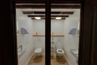 Deux toilettes séparées par une cloison, chacune équipée d'un lavabo, d'un miroir et d'un éclairage au plafond.