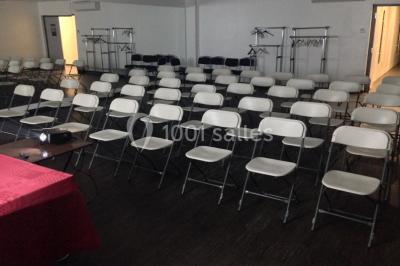 Vue d'un jardin clôturé avec une pelouse, des plantes en pot rouge et un premier plan de feuilles de yucca.