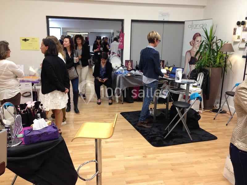 Des personnes discutent et explorent des stands dans une salle d'exposition lumineuse avec des produits variés.