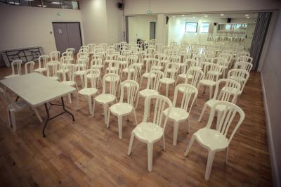 Vue d'un jardin clôturé avec une pelouse, des plantes en pot rouge et un premier plan de feuilles de yucca.