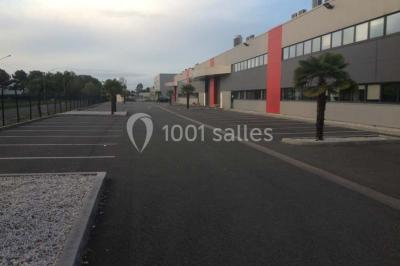 Vue d'un jardin clôturé avec une pelouse, des plantes en pot rouge et un premier plan de feuilles de yucca.