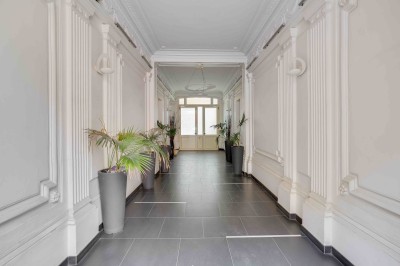 Façade d'un immeuble haussmannien avec balcons en fer forgé et fenêtres alignées sur plusieurs étages.