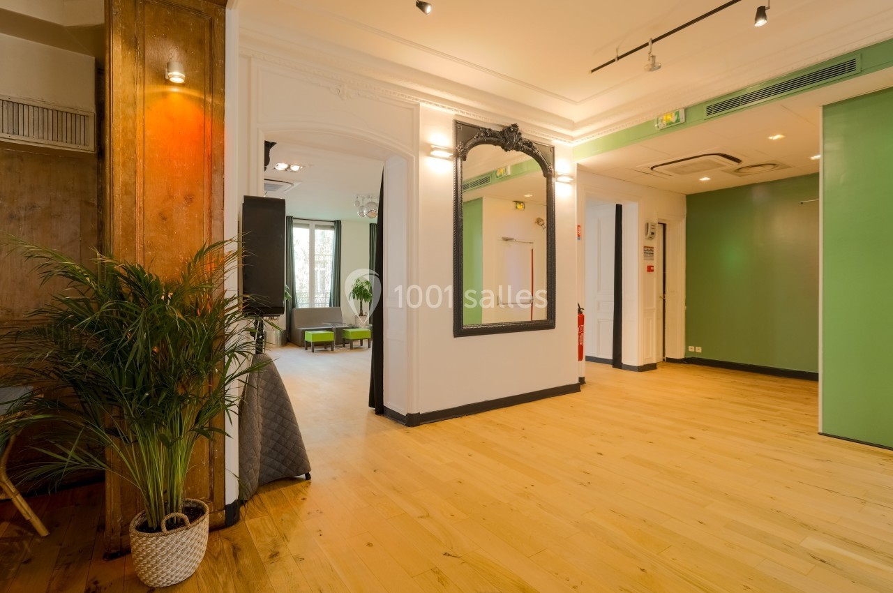 Salon Lafayette – espace cocktail et soirée privée à Paris Opéra Intérieur lumineux avec parquet, murs blancs, miroir encadré noir, plantes et portes vertes.