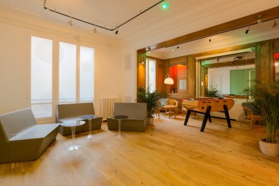 Miniature Salon Lafayette – espace modulable pour cocktail et soirée Salon lumineux avec parquet en bois clair, cheminée, fauteuils bleus et moulures au plafond.