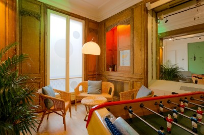 Miniature Salon Lafayette – espace sonorisé pour événement privé Salon lumineux avec parquet en bois clair, cheminée, fauteuils bleus et moulures au plafond.