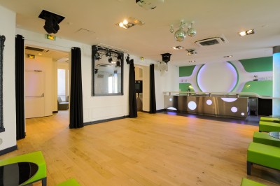 Miniature Salon Lafayette – salle de réception jusqu'à 100 personnes à Paris Salon lumineux avec parquet en bois clair, cheminée, fauteuils bleus et moulures au plafond.