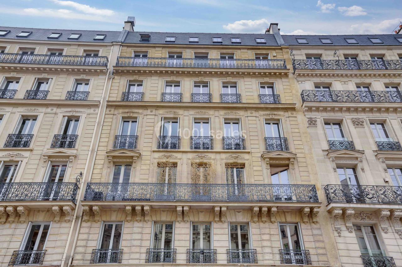 Façade d'un immeuble haussmannien avec balcons en fer forgé et fenêtres alignées sur plusieurs étages.