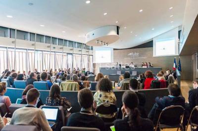 Un groupe de musiciens joue sur scène pendant qu'un public danse dans une salle éclairée et animée.