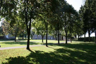 Terrain en cours d'aménagement avec une surface en gravier, entouré de verdure et proche d'un espace de jeux clôturé.