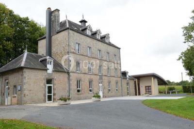 Terrain en cours d'aménagement avec une surface en gravier, entouré de verdure et proche d'un espace de jeux clôturé.