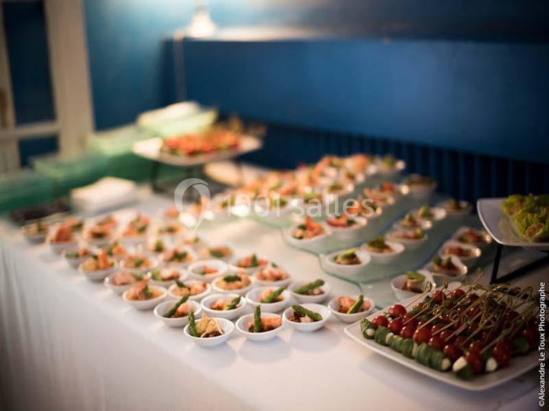 Buffet avec des verrines, brochettes de tomates et divers plats disposés sur une nappe blanche.
