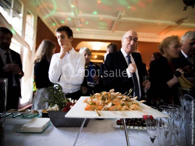 Plateau de brochettes apéritives sur une table lors d'un événement, avec des invités en arrière-plan.