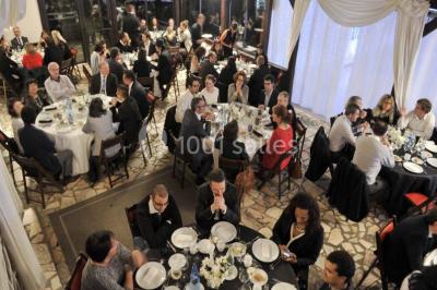 Jardin avec pelouse, tables et chaises rouges, scène en bois, entouré d'arbres et d'une maison à colombages.