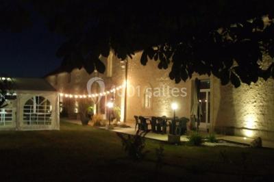 Miniature Location salle Chauvigny (Vienne) - Les Gîtes d’Isel #22 Terrasse avec table, chaises en plastique et parasol, située devant une maison en pierre avec jardin gazonné.