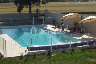Miniature Location salle Chauvigny (Vienne) - Les Gîtes d’Isel #23 Terrasse avec table, chaises en plastique et parasol, située devant une maison en pierre avec jardin gazonné.