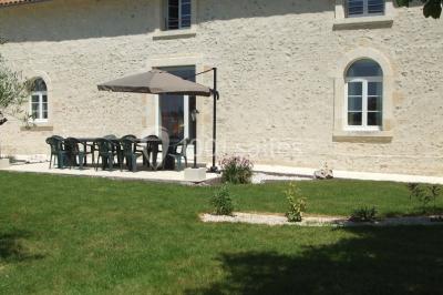 Miniature Location salle Chauvigny (Vienne) - Les Gîtes d’Isel #24 Terrasse avec table, chaises en plastique et parasol, située devant une maison en pierre avec jardin gazonné.