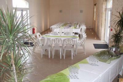 Miniature Location salle Chauvigny (Vienne) - Les Gîtes d’Isel #8 Terrasse avec table, chaises en plastique et parasol, située devant une maison en pierre avec jardin gazonné.