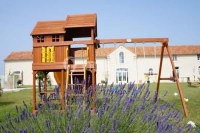 Miniature Location salle Chauvigny (Vienne) - Les Gîtes d’Isel #10 Terrasse avec table, chaises en plastique et parasol, située devant une maison en pierre avec jardin gazonné.