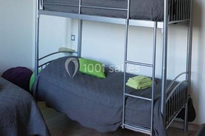 Miniature Location salle Chauvigny (Vienne) - Les Gîtes d’Isel #17 Terrasse avec table, chaises en plastique et parasol, située devant une maison en pierre avec jardin gazonné.