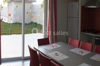 Miniature Location salle Chauvigny (Vienne) - Les Gîtes d’Isel #20 Terrasse avec table, chaises en plastique et parasol, située devant une maison en pierre avec jardin gazonné.