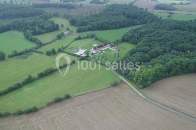 Chambre mansardée avec quatre lits simples, couvertures bleues et étagère en bois clair contre un mur gris.