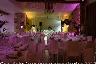 Chambre mansardée avec quatre lits simples, couvertures bleues et étagère en bois clair contre un mur gris.