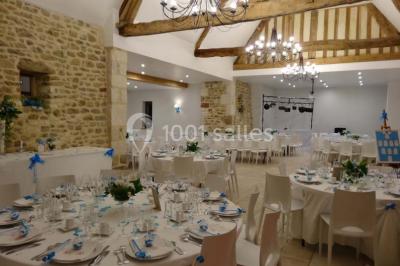 Chambre mansardée avec quatre lits simples, couvertures bleues et étagère en bois clair contre un mur gris.
