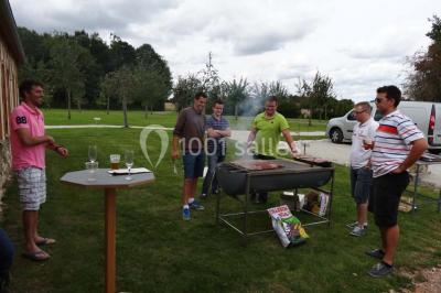 Chambre mansardée avec quatre lits simples, couvertures bleues et étagère en bois clair contre un mur gris.