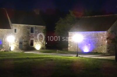 Chambre mansardée avec quatre lits simples, couvertures bleues et étagère en bois clair contre un mur gris.