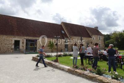 Chambre mansardée avec quatre lits simples, couvertures bleues et étagère en bois clair contre un mur gris.