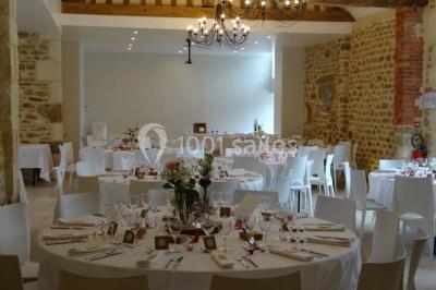 Chambre mansardée avec quatre lits simples, couvertures bleues et étagère en bois clair contre un mur gris.