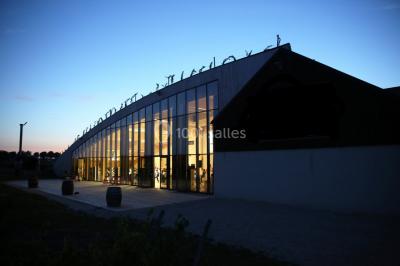 Cabane en bois arrondie dans un champ verdoyant sous un ciel bleu clair.
