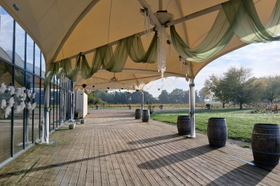 Cabane en bois arrondie dans un champ verdoyant sous un ciel bleu clair.