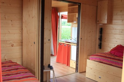 Deux cabanes en bois entourées de vignes et de verdure sous un ciel bleu dégagé.