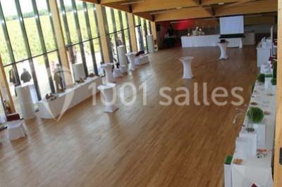 Salle lumineuse accueillant un salon avec des stands, des visiteurs et des tables exposant divers produits et services.