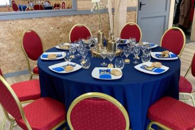 Chambre simple avec un lit double, une table en bois, une chaise et une lumière murale, donnant sur une porte vitrée.