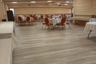 Chambre simple avec un lit double, une table en bois, une chaise et une lumière murale, donnant sur une porte vitrée.