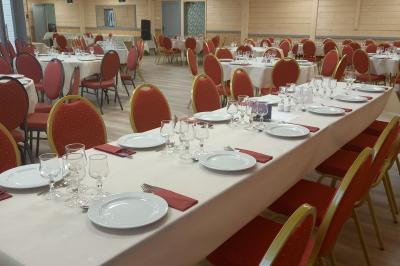 Chambre simple avec un lit double, une table en bois, une chaise et une lumière murale, donnant sur une porte vitrée.